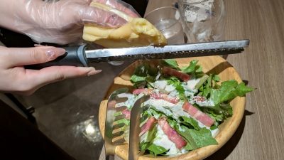 目の前で削るラクレットチーズとカリカリベーコンのシーザーサラダ（削り中）｜Cheese Meets Meat YOKOHAMA